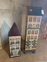 Both wooden cabinets shown side-by-side in basement setting with visible painted townhome details on facades.