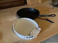 Photo showing the cast iron skillet and two white ceramic quiche dishes stacked on a counter.