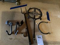 Photo showing five metal items on a surface: cheese slicer, trivet, fork, and two curtain tiebacks.