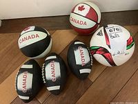 Photo of six small balls including two Canada themed basketballs, three mini Canadian footballs, and one Adidas mini soccer ball