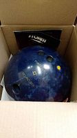 Photo of the bowling ball inside a box showing the top with finger holes and Power Control branding