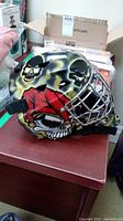 Side view of ITECH goalie helmet showing skull artwork and straps.