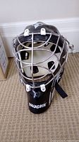 Top front view of black Vaughn goalie helmet showing cage face guard and ventilation holes