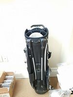 Full view of black and white Tourtec golf bag standing upright with carry strap and stand legs visible.