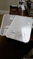 Photo showing both Modern Bevel boards, one dry erase and one linen bulletin, in original packaging on a surface.