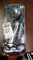 Front view of Peerless shower head in sealed packaging with product details visible on the front card insert.