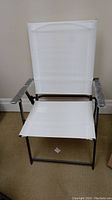 Single white sling folding patio chair unfolded examined to show material and frame
