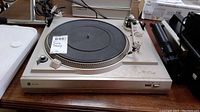 Top view of the turntable showing silver metal body, black platter mat, and control knobs.