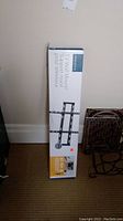 Original product box standing against a wall showing front view with Insignia TV wall mount branding and compatible TV size range.