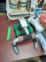 Pair of green 5 lb neoprene dumbbells next to one push-up bar on a shelf with other items.