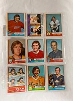 Front view of nine vintage hockey cards arranged in three rows inside a plastic sleeve.