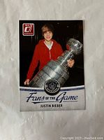Front side of the hockey card showing Justin Bieber holding the Stanley Cup trophy wearing a red hoodie, marked Donruss 10-11 Fans of the Game series.
