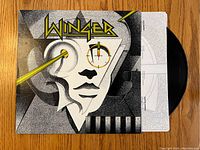 Vinyl record album by Winger with original cover partially open on wooden surface