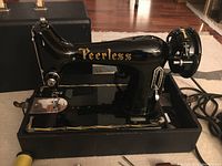Peerless portable black sewing machine with Needlelite motor, showing side profile with power cord and foot pedal