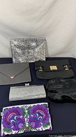 Front view of five women's clutches/bags showing variety of styles and colors