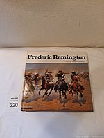 Front cover view of the hardback book 'Frederic Remington' featuring a dust jacket with a Western scene painting of four horsemen.