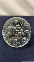 Top view of clear glass paperweight showing embedded bubbles inside the glass.