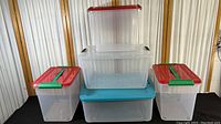 Five clear plastic storage containers stacked and arranged showing lids and sizes