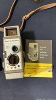 Bell & Howell 323 camera front detail with lens, control dial, and manual
