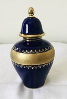 Front view of the vintage lidded cobalt blue porcelain jar with gold accents on body and lid showing overall shape and height.