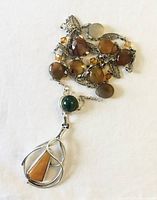 Long crystal natural stone pendant necklace; sterling silver pendant with green and orange stones, silver tone chain with amber and brown faceted beads