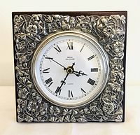 Front view of Royal Selangor clock showing detailed pewter floral frame and clear Roman numeral face