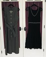 Front view of two black sleeveless summer dresses hanging on hangers