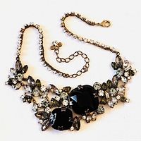 Full view of the vintage statement necklace showing two large smoky topaz crystals in the center with surrounding green and clear decorative crystals and clear rhinestones on chain.