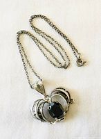 Pendant displayed with chain coiled, showing the three-dimensional heart design and silver details.