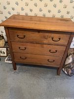 Front view of wooden dresser showing three drawers with metal handles and wood finish.