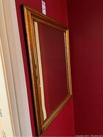 Side angle view showing the mirror mounted on a red wall, highlighting overall shape and size.