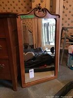 Full front view of the rectangular mirror with wood frame and decorative top, showing overall condition and proportion.