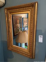 Front view of one ornate gold-tone framed mirror showing detailed carving and clear reflective glass with some wear on the frame.