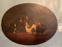Oval wood panel painting featuring a cat and dog lying side by side showing overall shape and color.