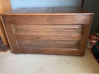 Front view of vintage wood trunk showing paneled front and flat lid