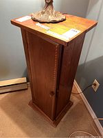 Full front and side view of the vintage wood pedestal cabinet showing overall shape and top surface.