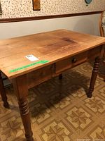 Wooden table with attached drop leaf and visible wear marks on top surface and legs.