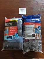 Photo of two unopened 5-packs of men's large boxers, one Hanes and one Gildan, showing packaging front with product information.