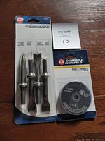 Photo showing 4 piece air chisel set and 5 cutoff discs in original packaging on wooden table