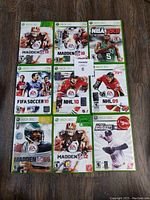 Nine Xbox 360 sports games arranged on wooden floor, showing their cover art clearly.