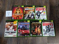 Top view of 7 Original Xbox games neatly arranged on a wooden surface, showing cover art for all games.