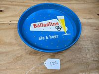 Top view of round metal serving tray with blue background showing Ballantine ale & beer logo and beer glass graphic. Tray is laid flat on wooden surface with a white tag numbered 122.