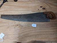 Vintage Disston Docking Saw laid flat on wooden surface showing full blade and wooden handle.