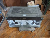 Front view of vintage hardwood tool chest showing brass-mounted corners and pasted old movie starlet images on front panels.