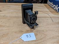 Front angle view showing the textured black body, extended bellows, lens, shutter, and exposure control lever.