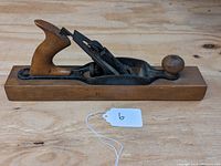 Side view of the wooden-bodied hand plane showing the rear handle and blade assembly.