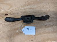 Full view of the black metal Stanley Rule & Level Co. spokeshave showing its two handles and blade area.