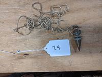 Full view of the vintage brass plumb bob resting on a wooden surface with attached coiled string.