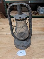Front angle photo of vintage metal railroad lantern with glass globe and wire guard.