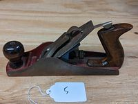 Side view of a Worth hand woodworking plane showing the wooden handles and metal body on a wooden surface.